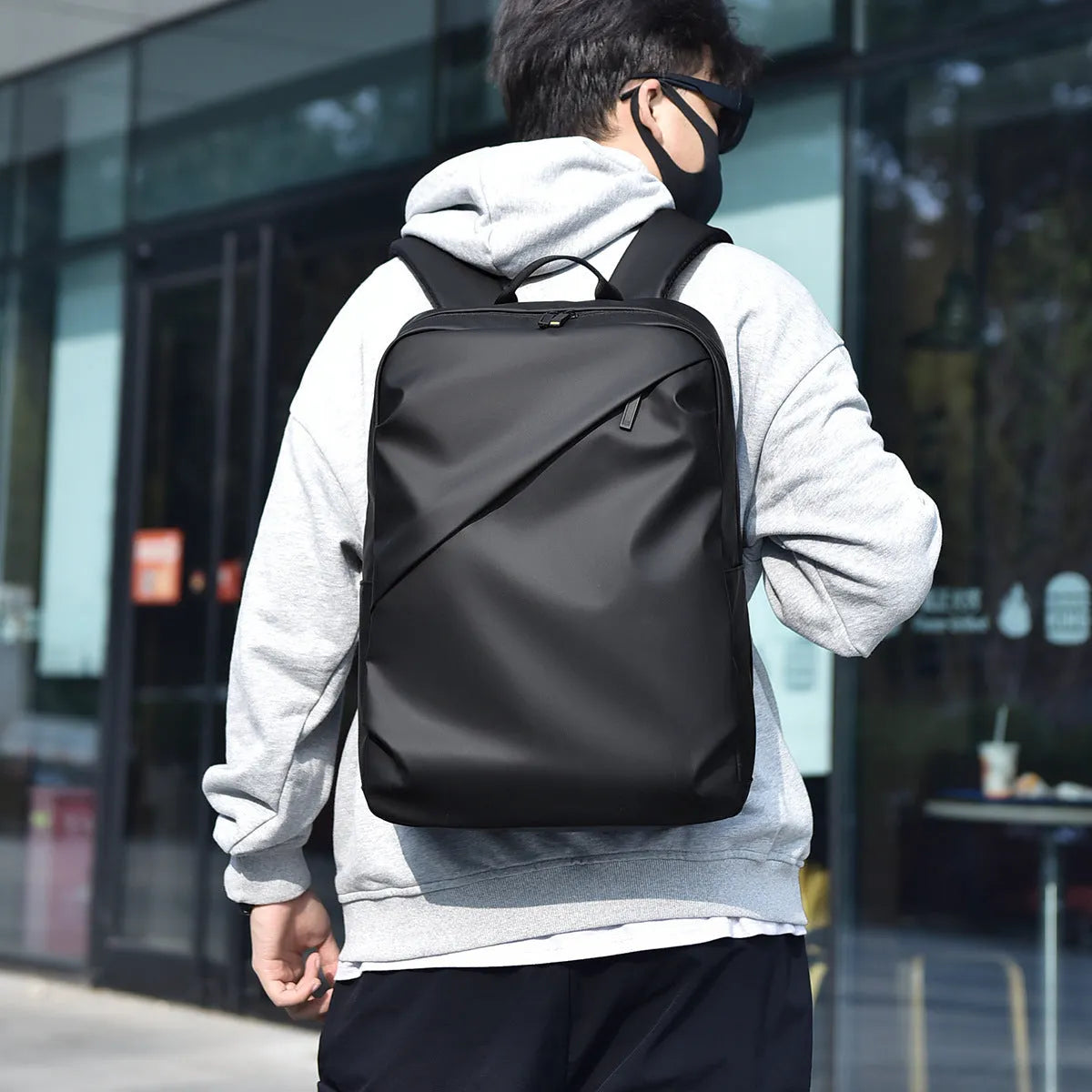 Men's large waterproof PU leather backpack in grey colour with visible stitching and laptop compartment.