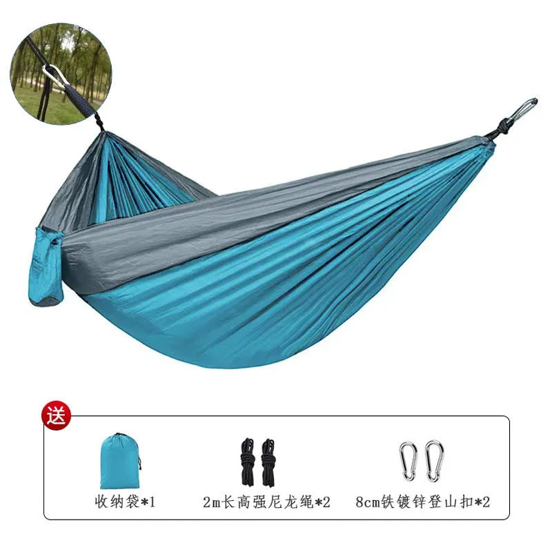 Blue parachute nylon camping hammock hung between two trees, showing its full 270cm length and 140cm width.