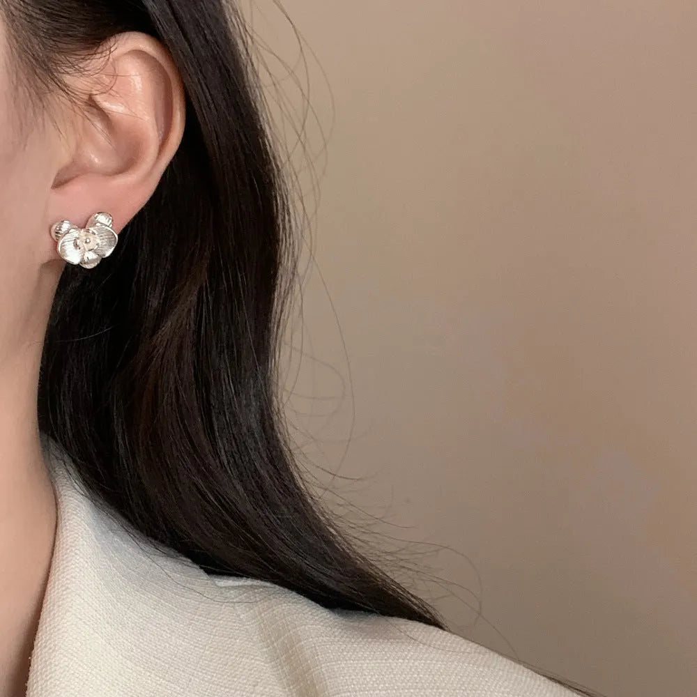 Women's retro flower earrings in copper with gold or silver electroplated finish showing petal detailing