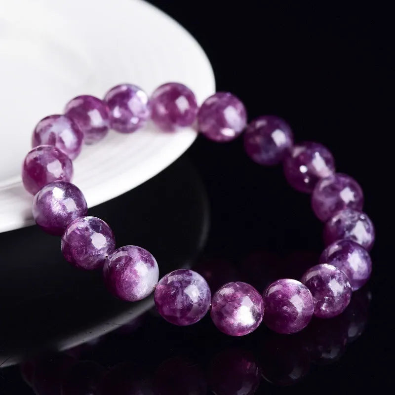 Geometric purple and pink polished crystal bracelet on a wrist, showing single strand of beads.