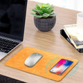 Brown leather-textured wireless charging mouse pad with a Micro USB cable on a wooden desk.