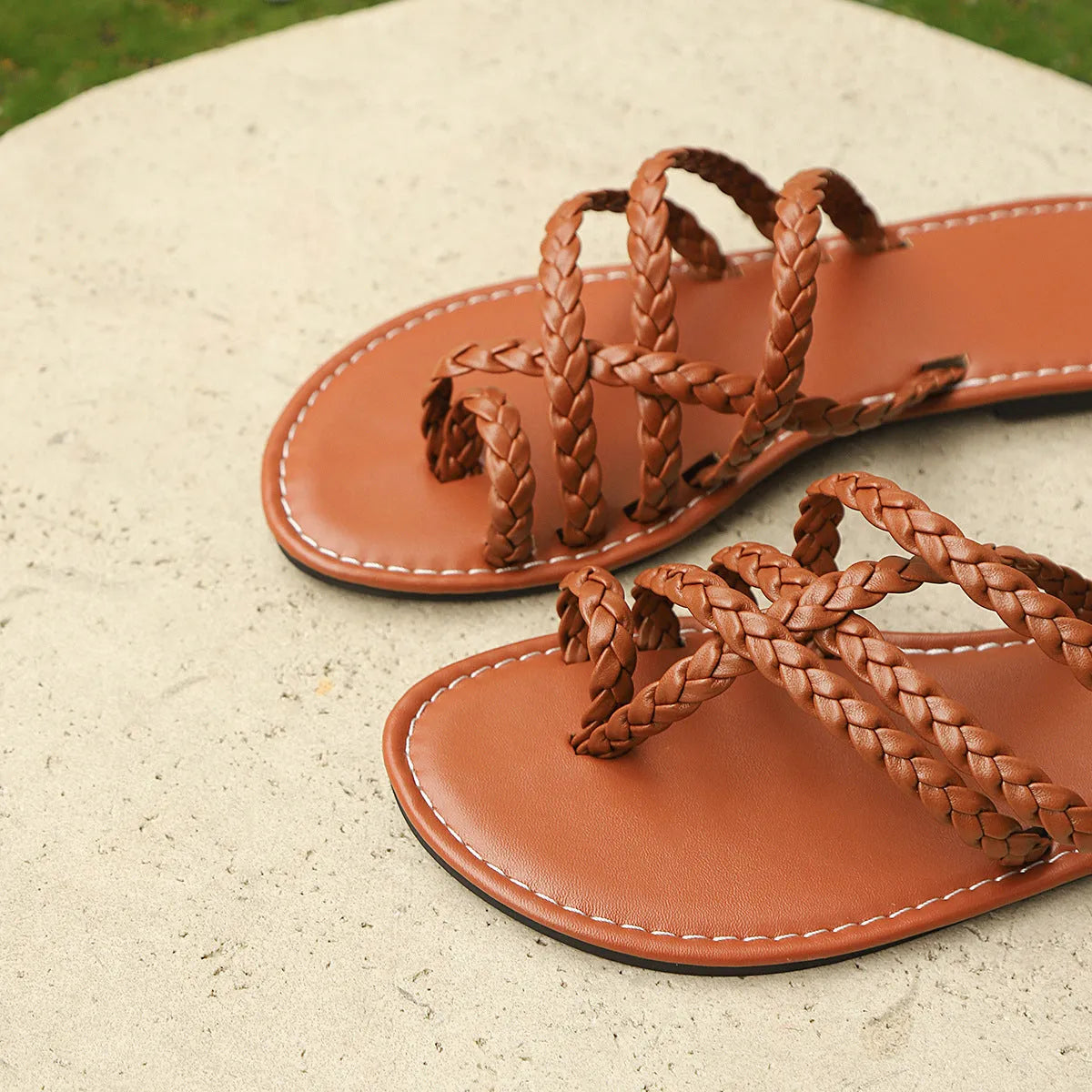Women's white woven flat sandals with an adjustable clip-toe strap on a wooden deck.