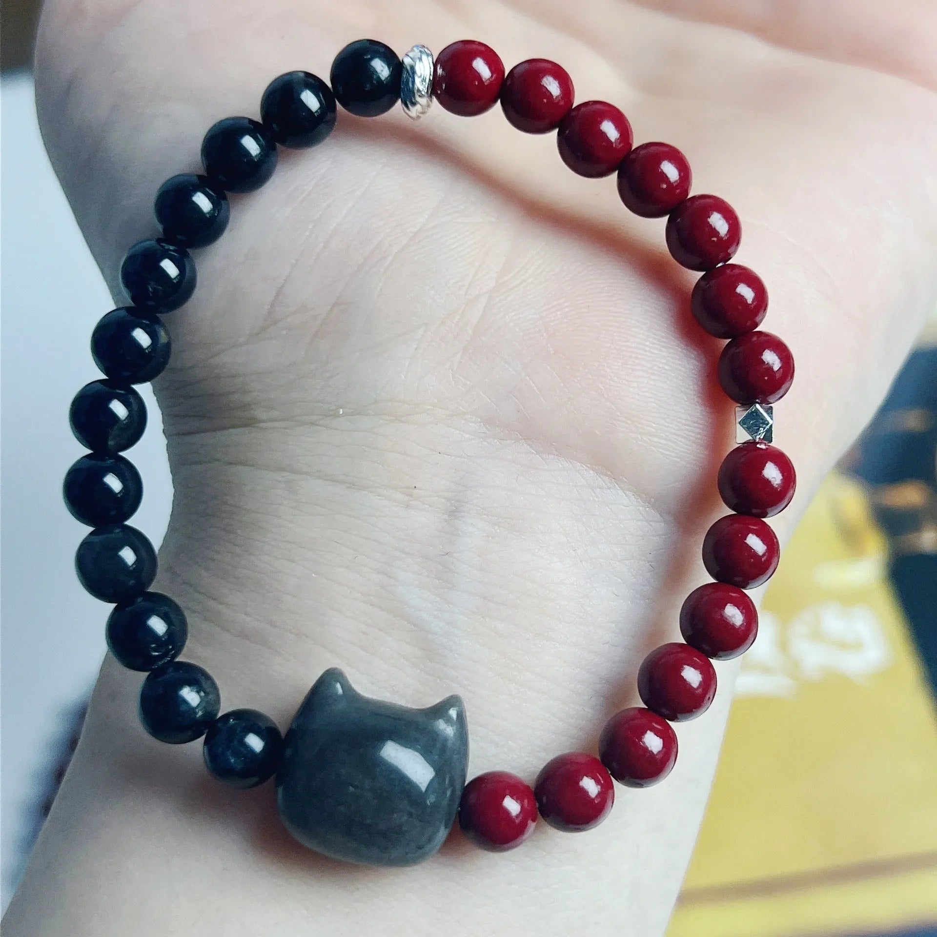 Obsidian-coloured cat charm on a colourful elastic bracelet strap.