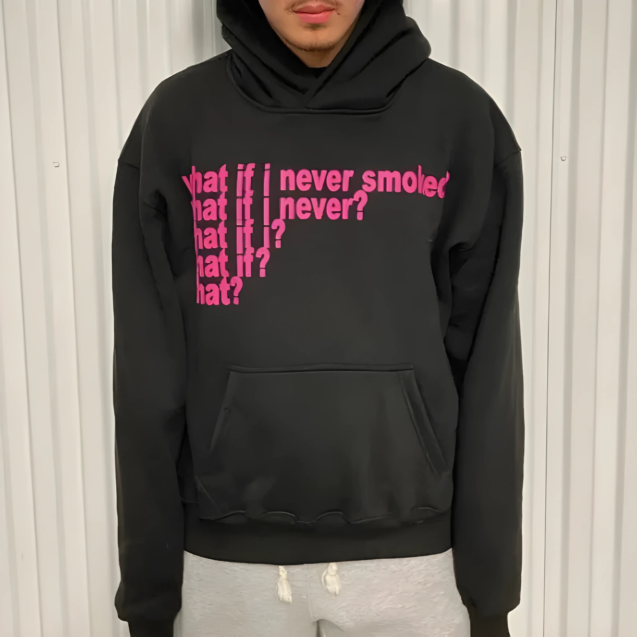 Black heavy hooded sweater with white letter print on chest, shown on a model.