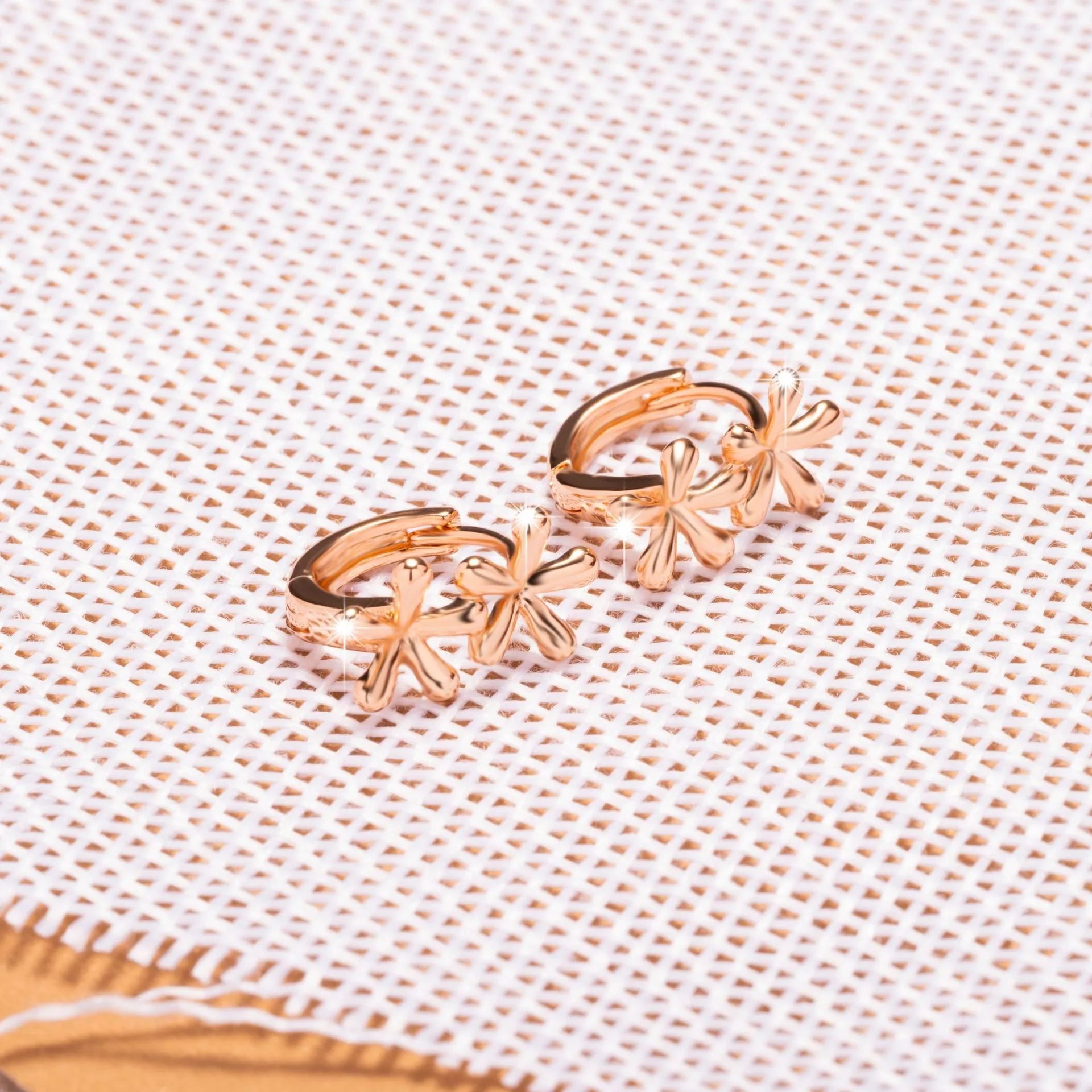 Rose gold electroplated earrings with a waterdrop shape and detailed floral petal etching on a white background.