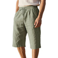 Man wearing loose-fit light khaki linen shorts with a drawstring waist and cropped leg.