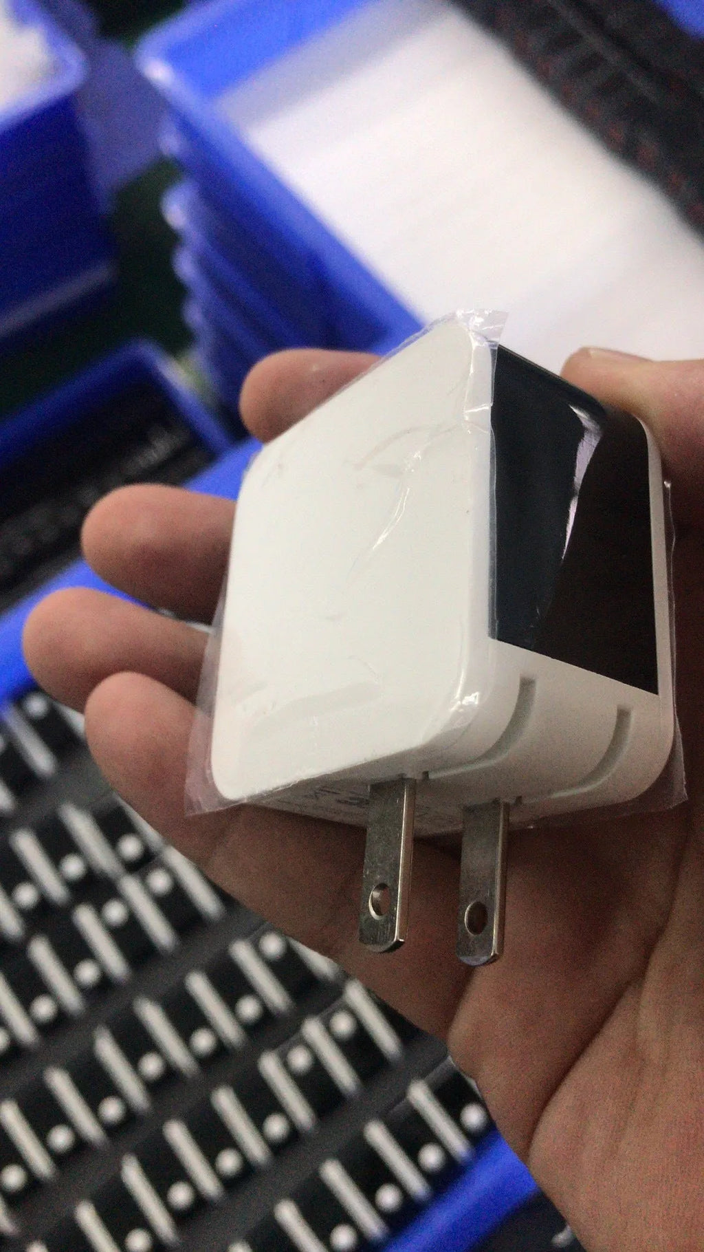 Compact black dual USB travel charger with a digital voltage display showing 5.0V, next to a UK plug.