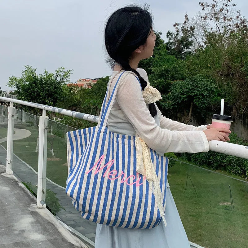 Blue striped letters printed on a pink, blue, and white striped cotton canvas bag for daily matching.