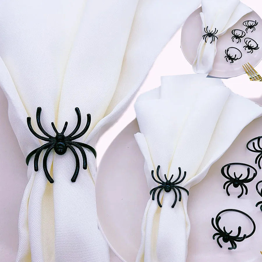 Six black alloy spider-shaped napkin rings on a dark table, showing detailed legs and a 5cm height.