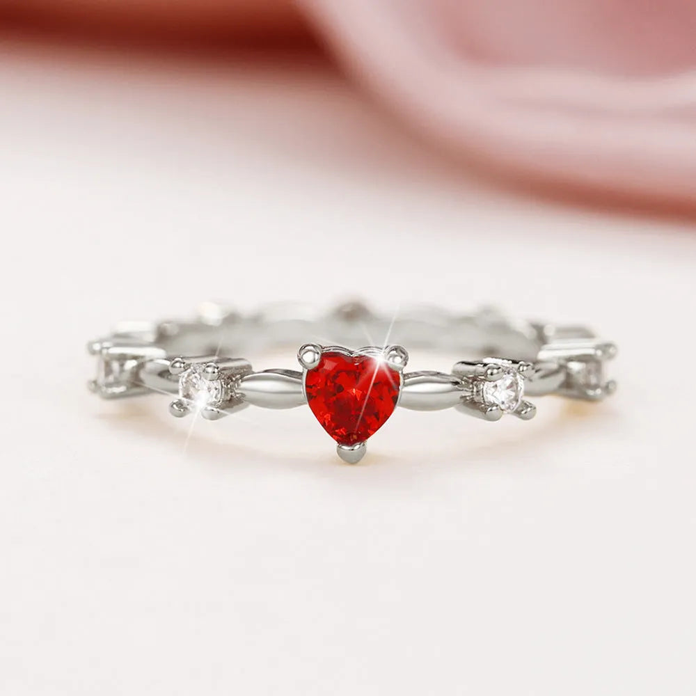 Copper fashion ring with peach heart zircon detail in gold or silver electroplating, shown on a finger.