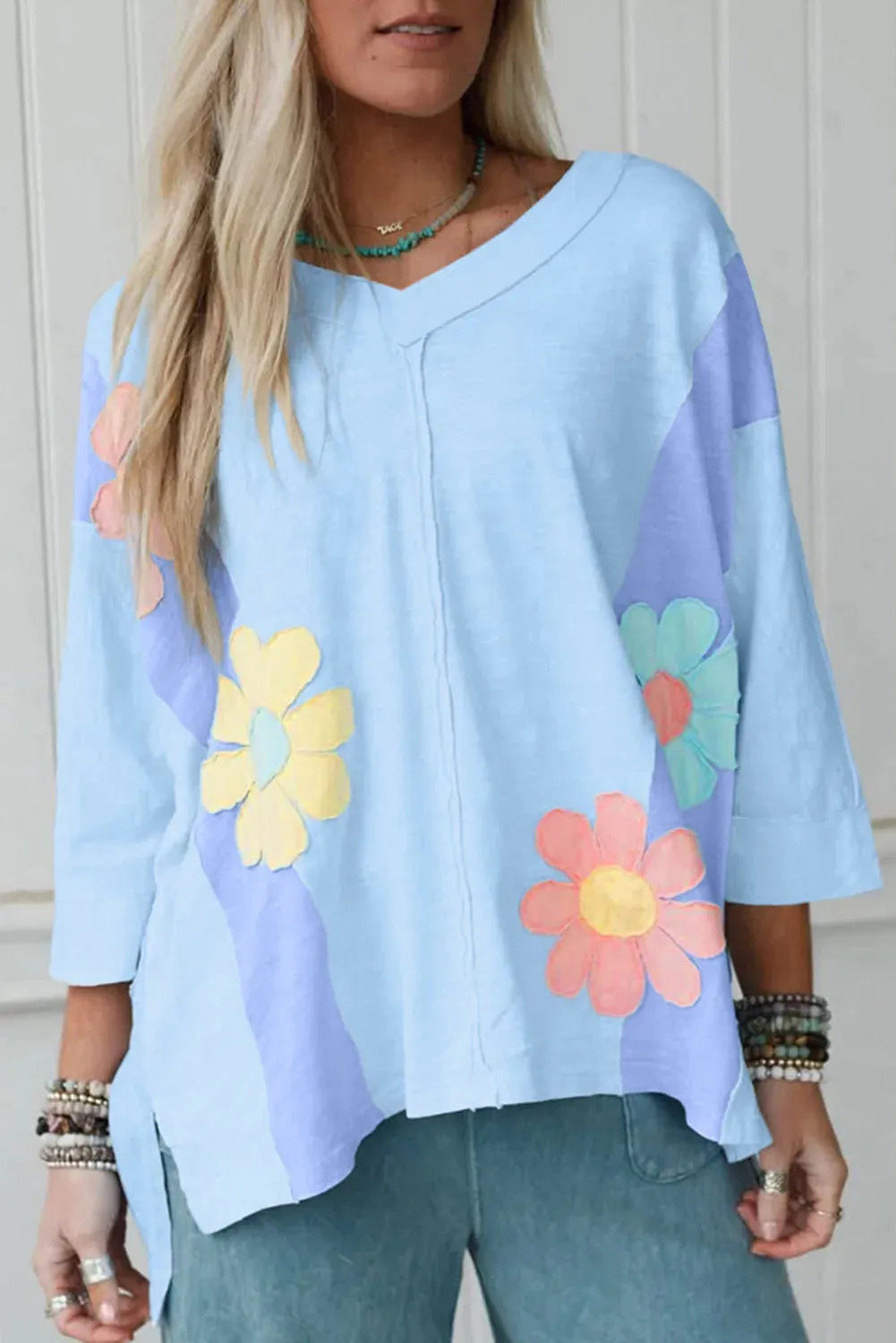 Light blue oversized T shirt with flower patch, exposed seams and bracelet sleeves in sizes S to XL