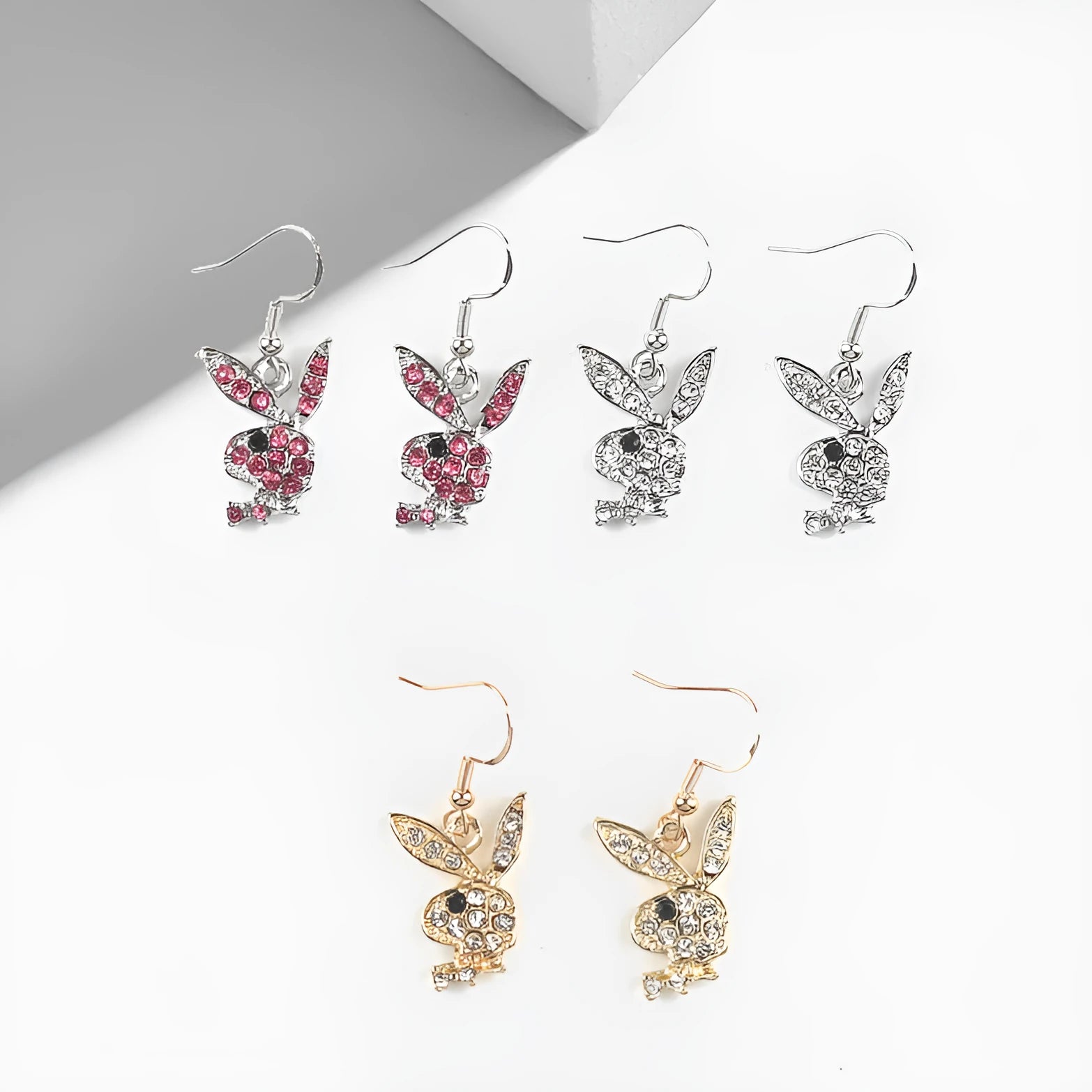 Close-up of a pair of cute rabbit-shaped stud earrings with sparkling cubic zirconia stones on a silver-coloured background.