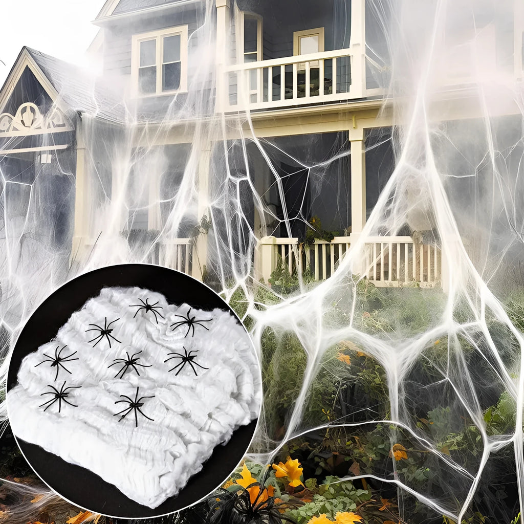 White cotton spider web Halloween decoration draped with plastic spiders on a dark background.