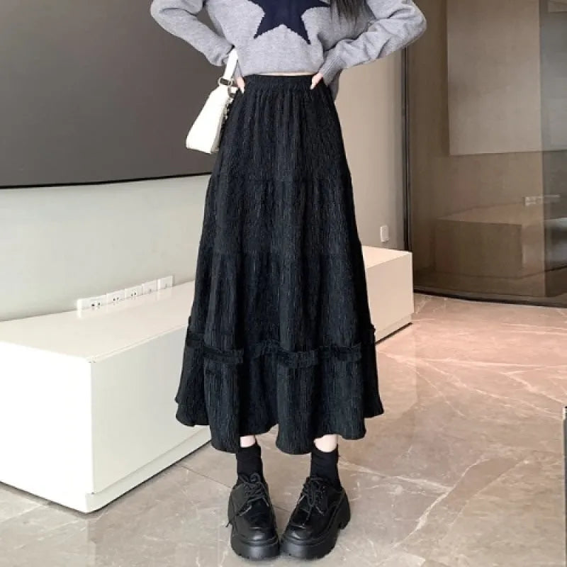 A woman wearing a beige corduroy A-line midi skirt with an elasticated waistband.