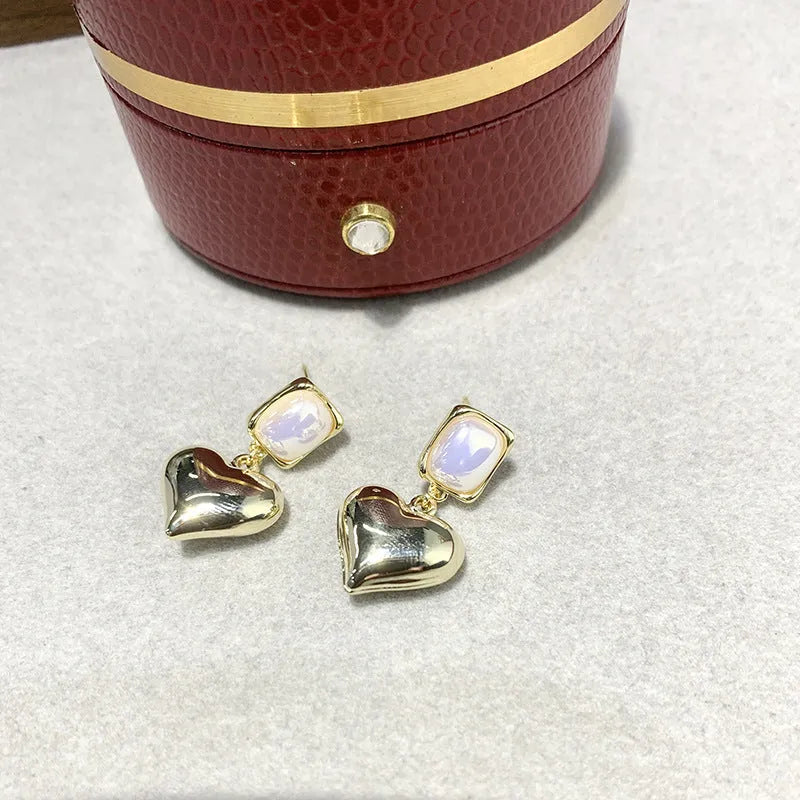 Small gold heart stud earrings with hypoallergenic metal finish on white background