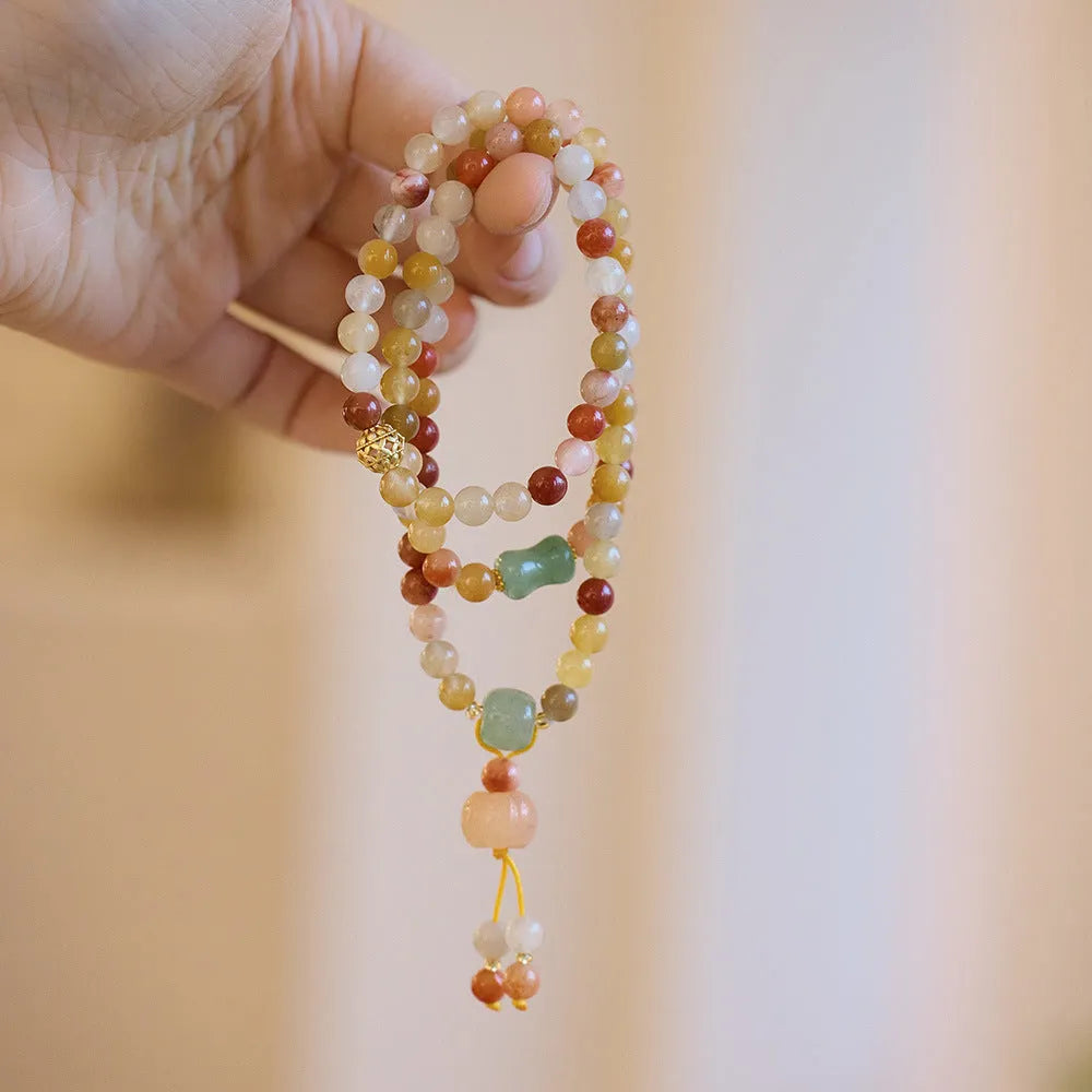 Women's handcrafted Jinsi Jade bracelet with pumpkin-shaped beads and tassels on a wrist.