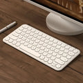White ultra-thin wireless keyboard and mouse set with a single USB receiver on a wooden desk.