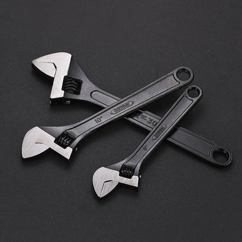 High carbon steel adjustable open-end wrench with black finish on a workbench.