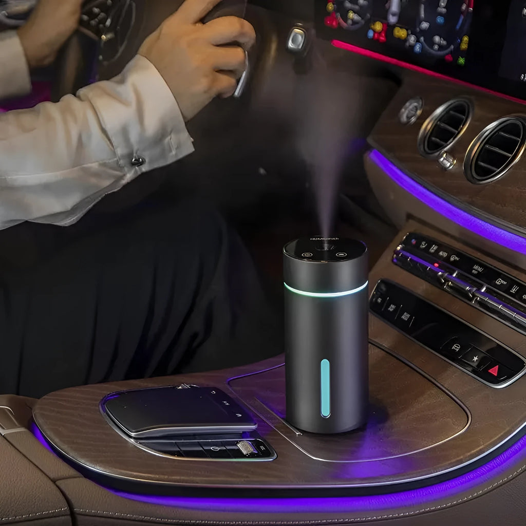 Black aluminium portable car humidifier and essential oil diffuser with USB cable on a desk.