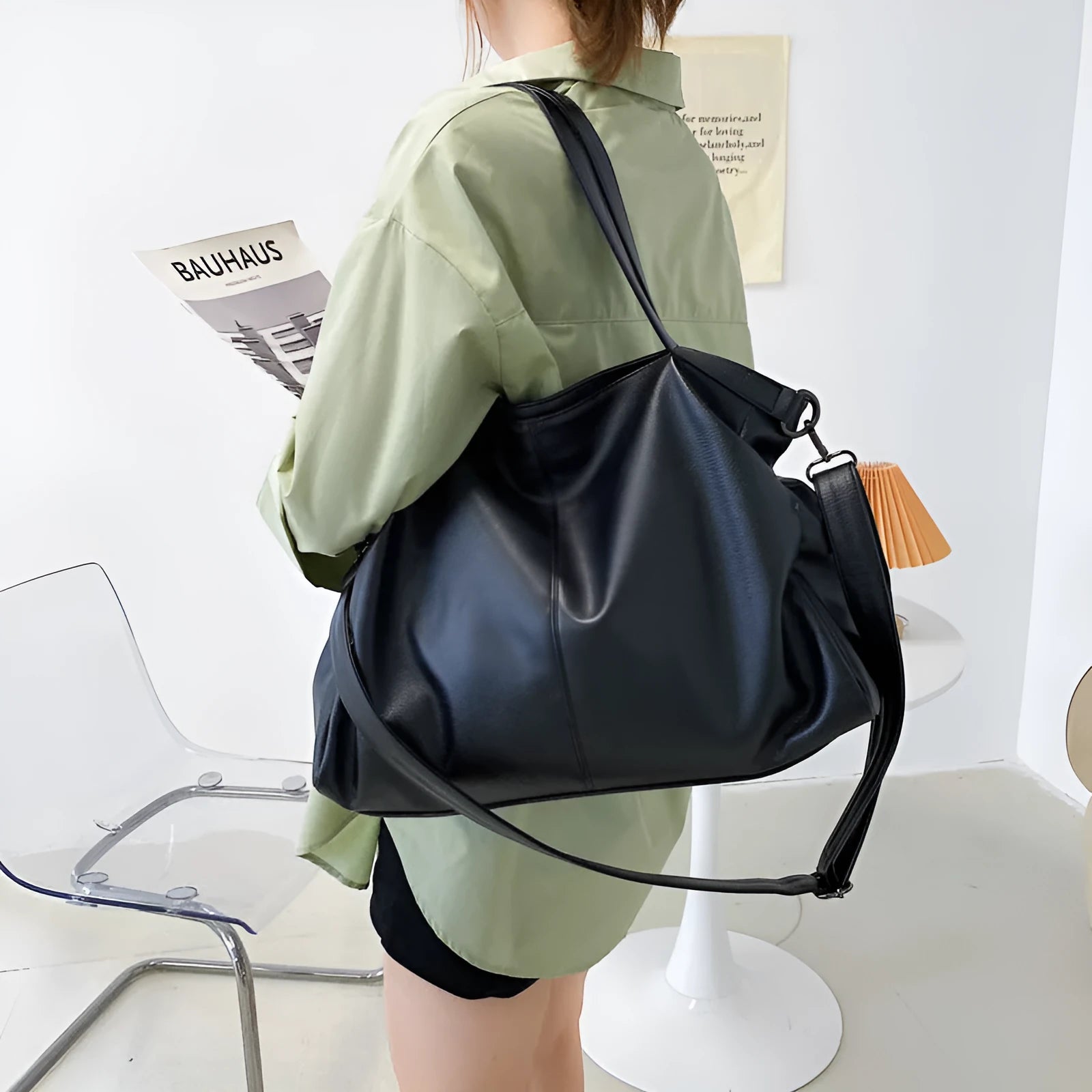 Large soft surface casual messenger bag in black showing horizontal shape and shoulder strap.