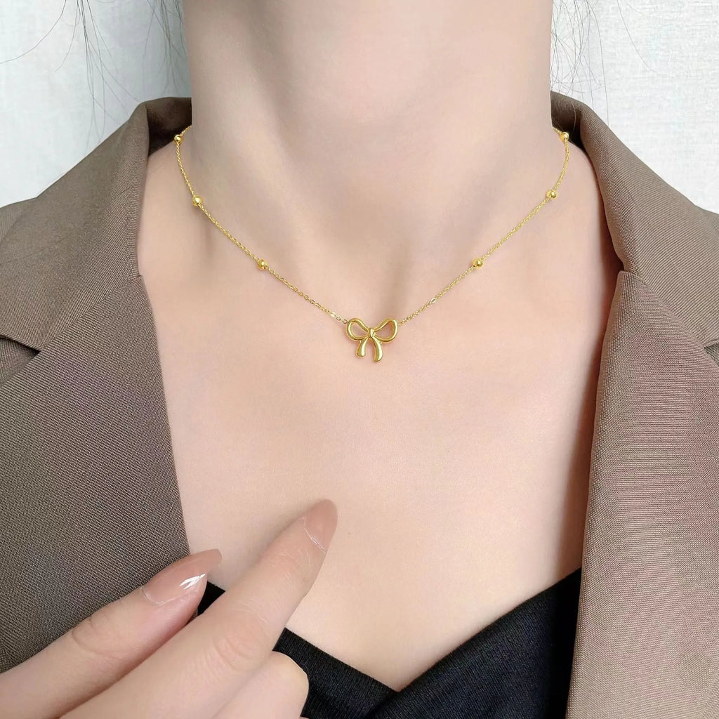 Gold electroplated titanium steel bow necklace with cross chain design showing adjustable length mechanism