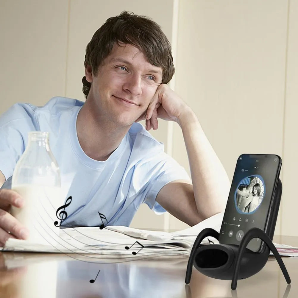 White mini chair shaped wireless charging stand holding a mobile phone on a desk.