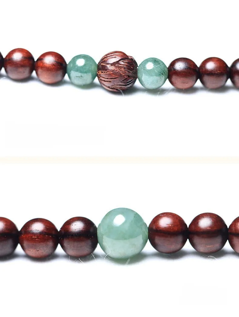 Close-up of a hand-carved rosewood beaded bracelet with 108 6mm beads and a carved Hotian jade pendant.
