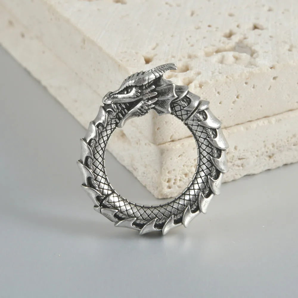Pair of large antique silver dragon-shaped earrings with geometric hollow-out design on a white background.