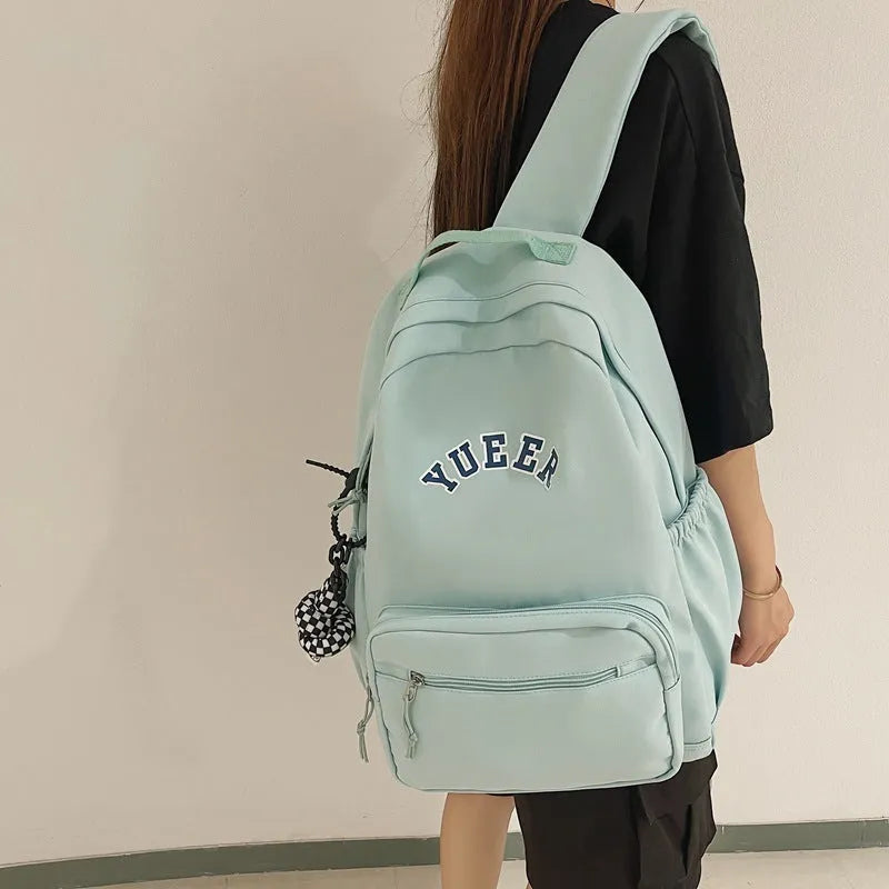 Simple nylon backpack for women, 32cm, with computer pocket, in five colours including black, blue, red, white, and light green.