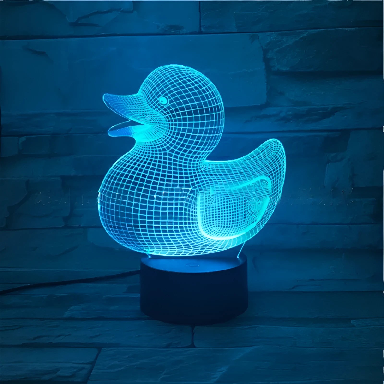 Yellow 3D duck-shaped LED night light with remote control on a table, showing soft multi-coloured glow.