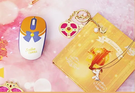 Pink Sailor Moon cartoon wireless mouse on a desk next to a laptop.