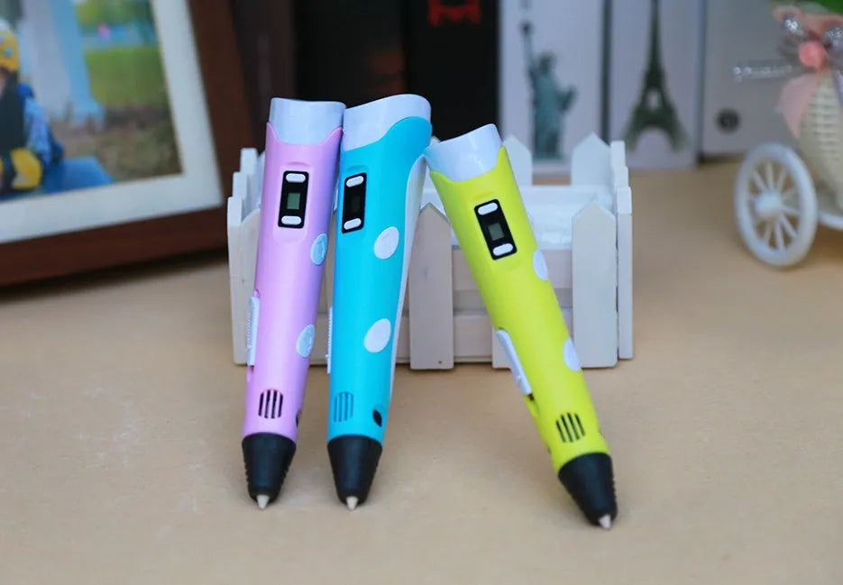 Yellow 3D printing pen with 12 colour PLA filament spools and UK power adapter on a white background