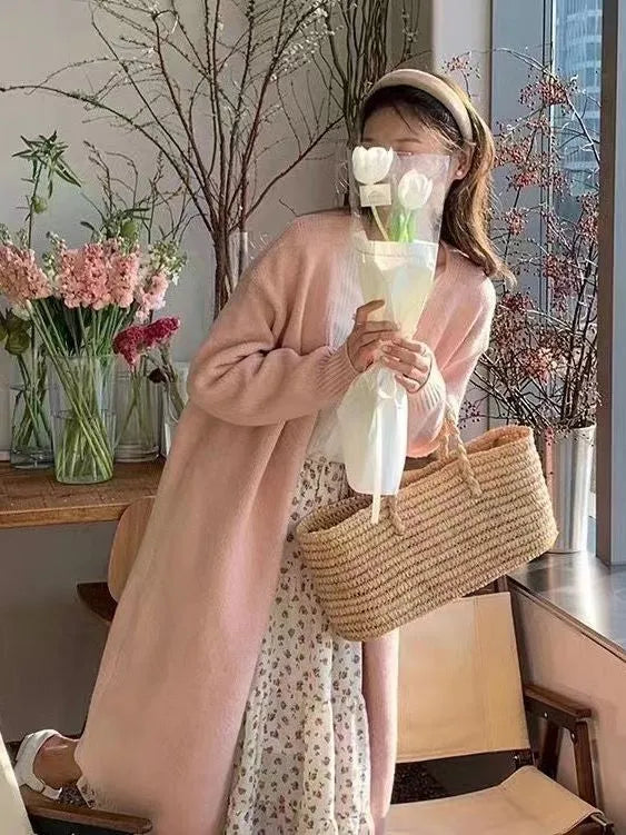 A woman wearing a khaki-colour, loose-fit knitted cardigan with a V-neck and long sleeves.
