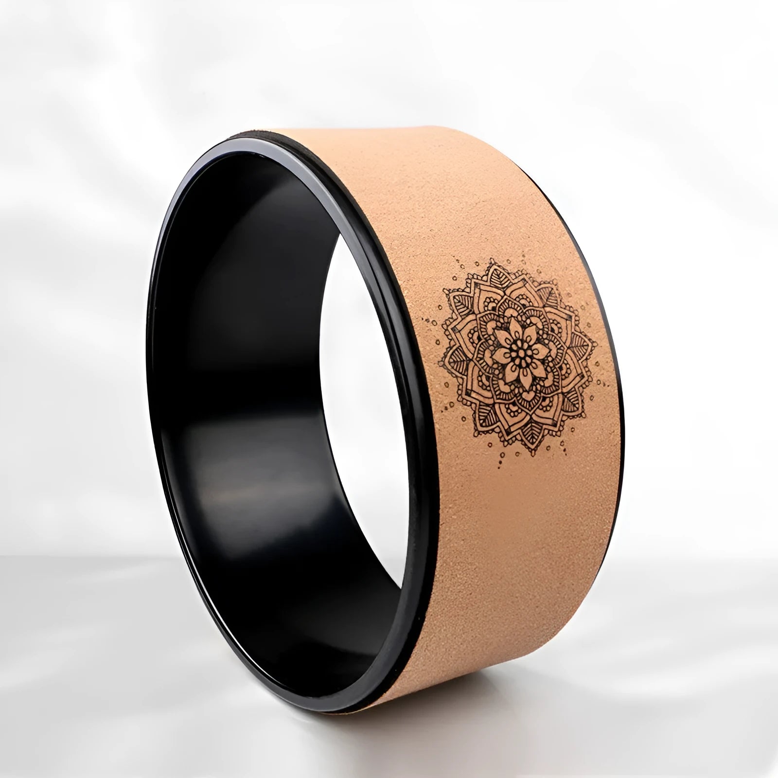 Brown cork yoga wheel with Mandala flower design on a wooden floor