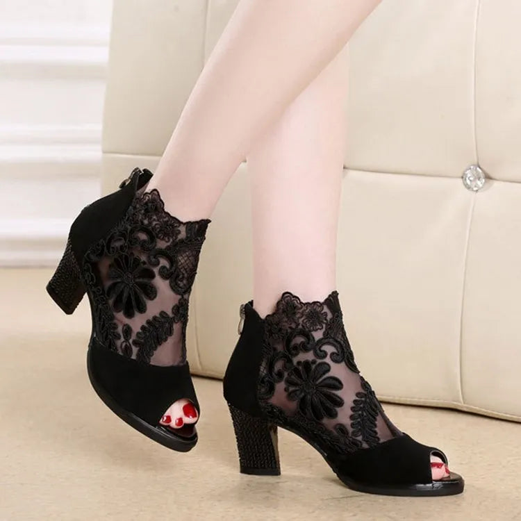 Lucyever women's black gladiator sandals with floral lace upper, square heel, and peep toe on a foot.
