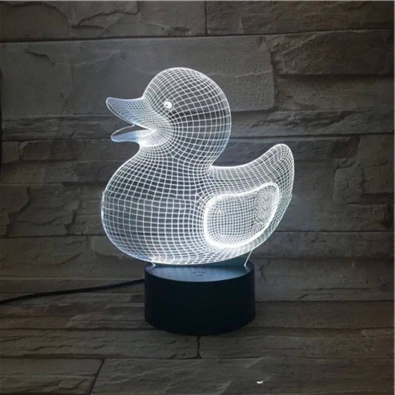 Yellow 3D duck-shaped LED night light with remote control on a table, showing soft multi-coloured glow.