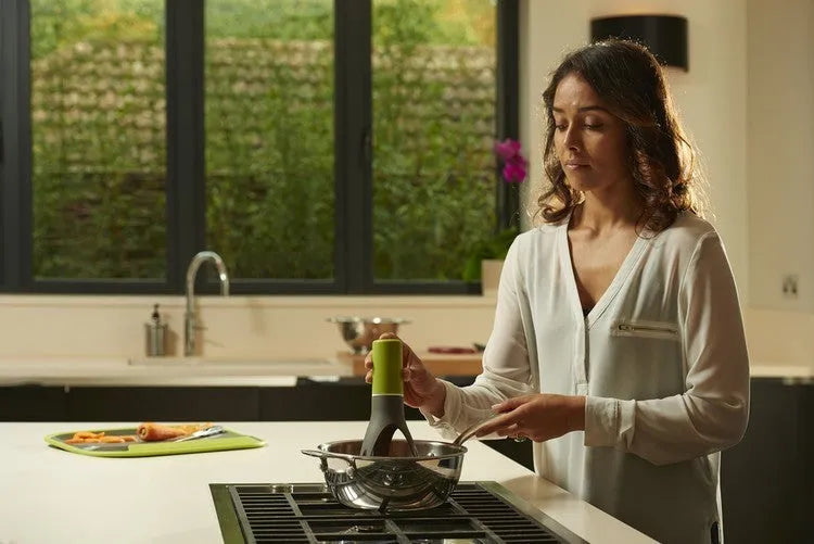 Green and grey automatic cooking mixer device for stirring sauces and soups.