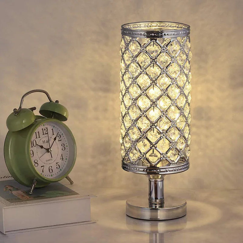 Modern crystal table lamp with gold metal base and hollow-carved crystal shade on a bedside table