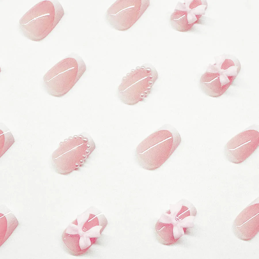 Set of 24 short, square, white-tipped French manicure false nails and a tube of nail glue on a pink background.