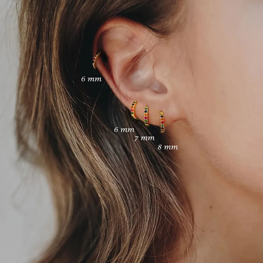 Circle-shaped perforated stud earrings in gold, rose gold, and silver colours on a white background.