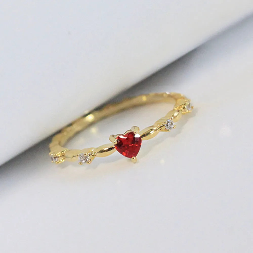Copper fashion ring with peach heart zircon detail in gold or silver electroplating, shown on a finger.