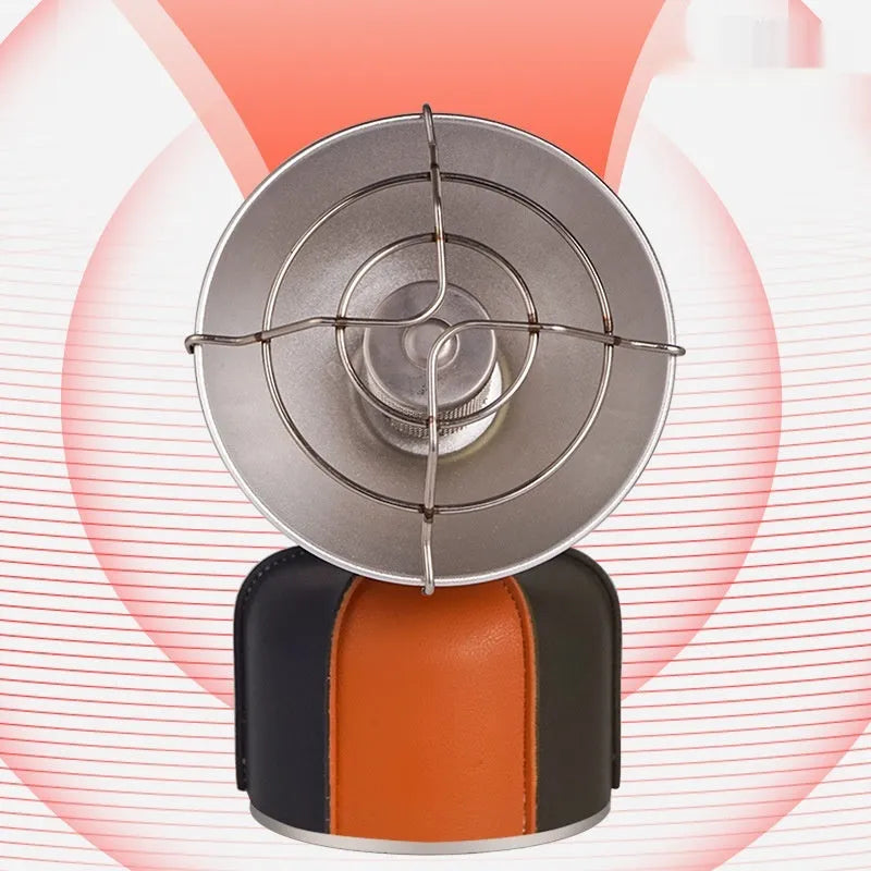 Black and orange mini portable camping stove with automatic ignition on a grassy outdoor surface.