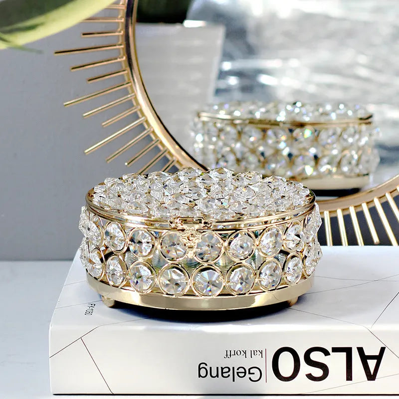 Transparent crystal glass jewelry storage box with a French gold-coloured metal frame on a table.
