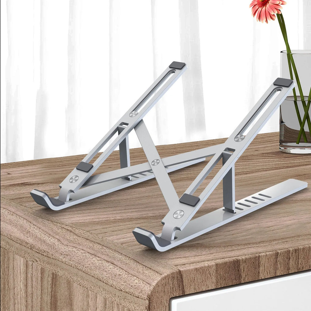 Silver aluminium laptop stand open at an angle next to a closed laptop.