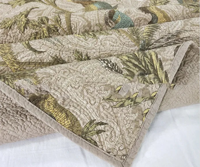 Blue American floral and bird pattern quilted cotton bedspread draped on a double bed