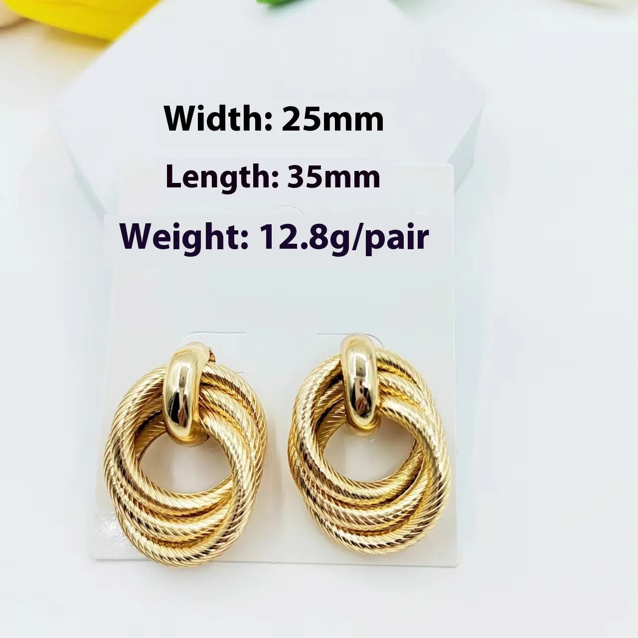 Gold metal geometric ring embossed twisted stud earrings on display