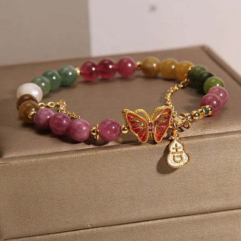 Close-up of a jade and tourmaline coloured agate bracelet with a butterfly-shaped gourd charm.