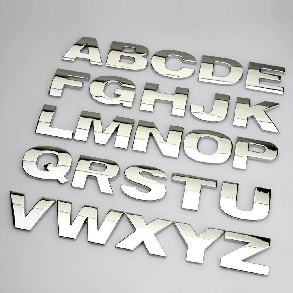 Close-up of a black zinc alloy 3D letter 'A' car bumper sticker on a silver vehicle panel.