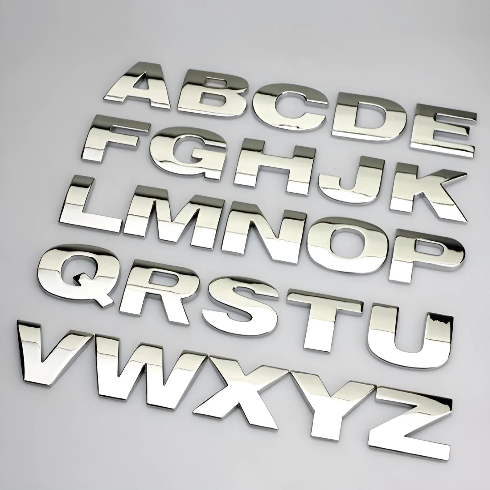 Close-up of a black zinc alloy 3D letter 'A' car bumper sticker on a silver vehicle panel.