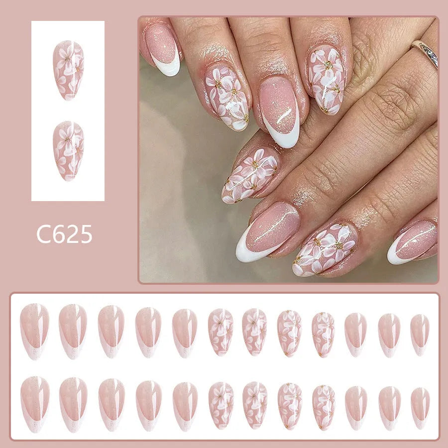 Short almond-shaped plastic false nails with glossy white French tips and pink glitter powder flower design.